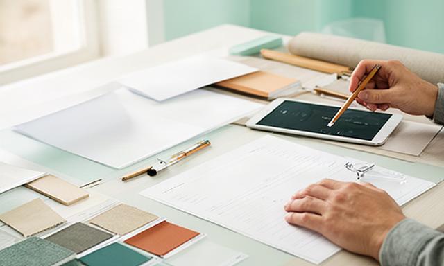 Persona che compila una richiesta di progetto su una scrivania luminosa