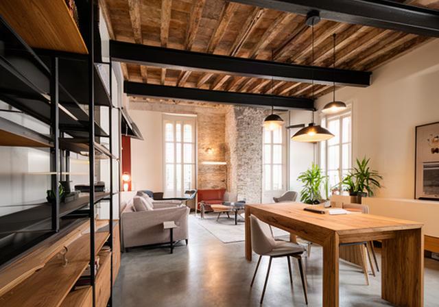 Loft industriale a Valverde con travi a vista, metallo nero e arredi in rovere